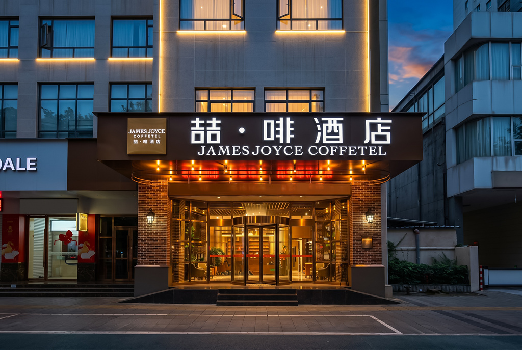 广元喆啡酒店门头夜景摄影,喆啡酒店招牌灯箱与旋转门入口暖光